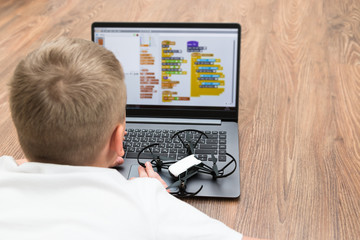 a teenage boy programs a copter drone on a scratch. stem education. modern technology and gadgets.