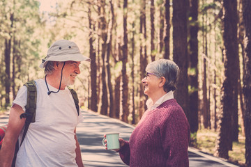 Old caucasian mature couple smile and enjoy during trekker wild vacation journey in a high pines forest at the mountain - alternative wild people travel together forever