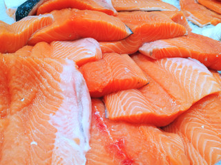 In the store (at home) in the refrigerator in the ice, fresh ready-to-cook (for sale) salmon fish is chopped (whole). Concept of: Fish for sale, Salmon, Sliced, Fresh writing, Market, Shop, Sale.