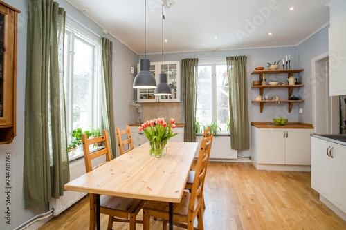 Fotografía kitchen table with orange tulips and green curtains by the windows white interio
