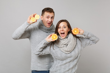 Wall Mural - Fun couple girl guy in gray sweaters, scarves together hold orange lemon isolated on grey wall background studio portrait. Healthy lifestyle ill sick treatment cold season concept. Mock up copy space.