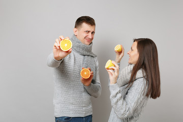 Wall Mural - Fun couple girl guy in gray sweaters, scarves together hold orange lemon isolated on grey wall background studio portrait. Healthy lifestyle ill sick treatment cold season concept. Mock up copy space.