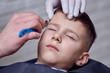 © Artem - Barber is using razor while making a new hairstyle to a cute European boy.