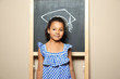 © New Africa - African-American child standing at blackboard with chalk drawn academic cap. Education concept