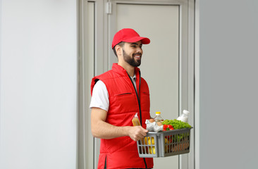 Canvas Print - Man holding basket with fresh products near entrance. Food delivery service