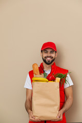 Canvas Print - Man holding paper bag with fresh products on color background. Food delivery service