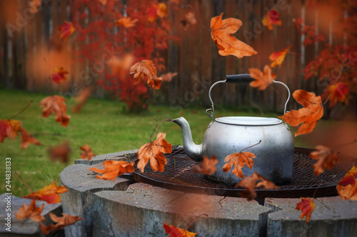 Autumn Scene Of Red Leaves Blowing Around A Kettle On The Grill Of