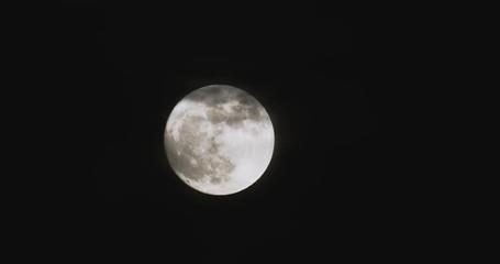Wall Mural - Time-lapse of full moon against dark black sky with partial clouds