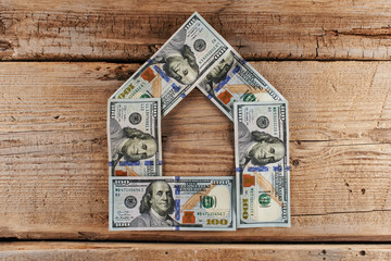 Dollars. American money in the shape of a house on a wooden background. Real estate loan concept