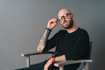 Wall Mural - Close-up portrait, modern young Caucasian man with beard and glasses posing gray background