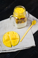 Wall Mural - Healthy breakfast muesli and yogurt with mango smoothie in glass mason jars, black background