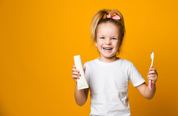 Wall Mural - Beauty girl holding toothbrush and winking isolated over yellow background