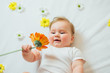 © kaloriya - Beautiful baby holding a flower on white blanket