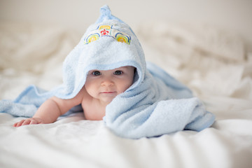 Wall Mural - Cute little baby boy, relaxing in bed after bath, smiling happily