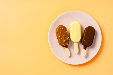 Wall Mural - Top view of three ice cream popsicles in pink plate