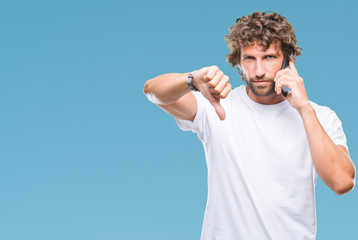 Poster - Handsome hispanic man model talking on smartphone over isolated background with angry face, negative sign showing dislike with thumbs down, rejection concept