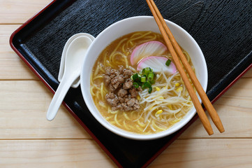 a bowl of gluten free instant ramen noodles topped with ground pork, fish cake and bean sprouts.