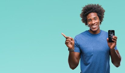 Wall Mural - afro american man holding broken smartphone over isolated background very happy pointing with hand a