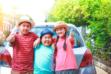 3 Asian children are standing, hugging each other, glad to go on a trip