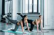 © LIGHTFIELD STUDIOS - beautiful multiracial sporty girls exercising on yoga mats and looking away in gym