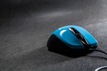 Small computer mouse plastic. Blue color. Black background. Black wire. A blank space for an inscription. Electronics.