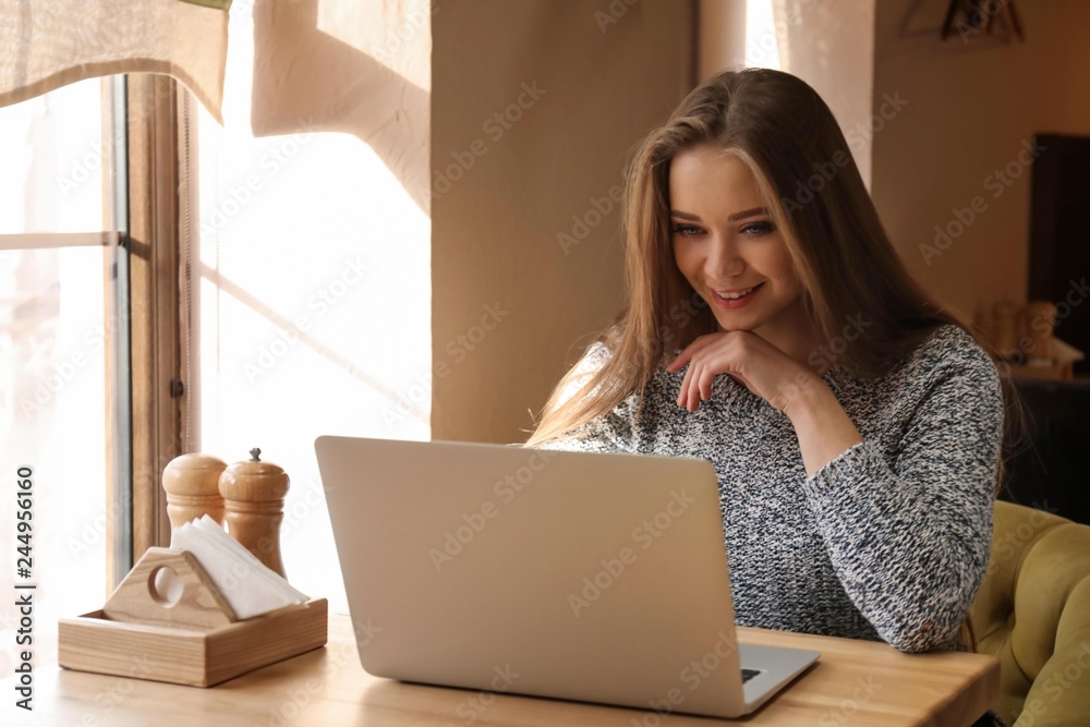 Young woman working on laptop in cafe