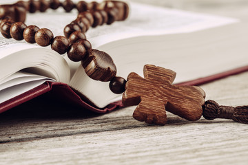 Bible and a crucifix on an old wooden table. Religion concept.