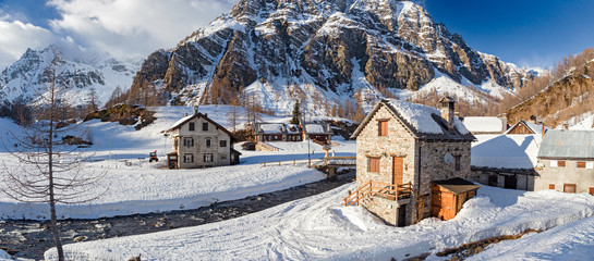 Panoramic view of the sunny snow-covered landscape of the village of Crampiolo, above the Alpe Devero in Piedmont, Italy.