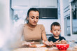 © komokvm - mom and son prepare dough from flour will bake bows