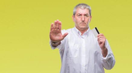 Canvas Print - Handsome senior man holding credit card over isolated background with open hand doing stop sign with serious and confident expression, defense gesture