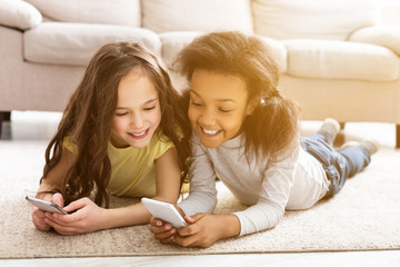 best friends using smartphones, lying on floor