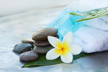 Two bottle with lotion and flower, towel and stone.