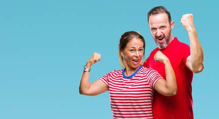 Middle age hispanic couple in love over isolated background showing arms muscles smiling proud. Fitness concept.