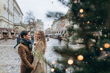 Beautiful romantic lovely couple laughing and have fun on the central square of the Christmas Europe city