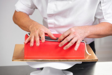 Wall Mural - Professional confectioner making delicious red cake, close up .