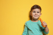 Adorable little boy with carrot on color background. Space for text