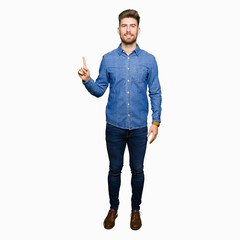 Young handsome blond man wearing casual denim shirt showing and pointing up with finger number one while smiling confident and happy.