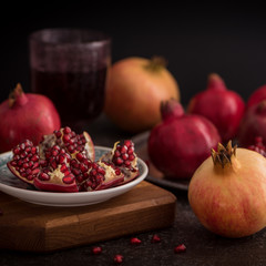 Wall Mural - A glass of pomegranate juice with fresh pomegranate fruits and seeds on rustic background. low key