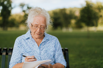 Senior woman writing down her memories into a notebook