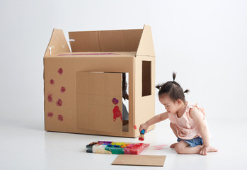 Asian little girl playing with paper house, in white background