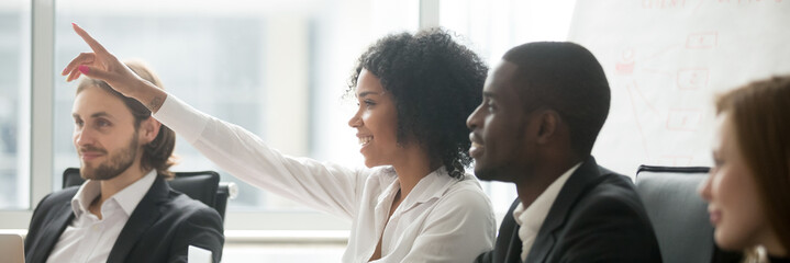 Diverse people sitting at boardroom, african woman raise hand ask question during seminar conference, corporate education or volunteer voting concept. Horizontal photo banner for website header design