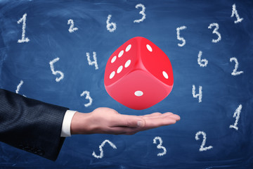 Poster - businessman hand and big red dice with random numbers on blue background