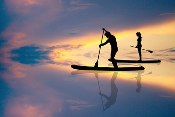 Wall Mural - couple standing on a paddle at sunset