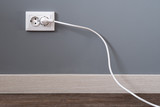 Fototapeta Sport - Power cord cable plugged into wall outlet