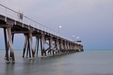 Fototapeta  - Morning photo of a jetty or pier with overcast skies and calm water