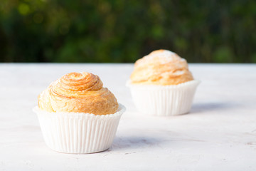 Fresh baked golden muffins on rustic wooden background shot in natural light