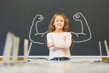 Mädchen In Schule Steht Vor Tafel Mit Muskeln
