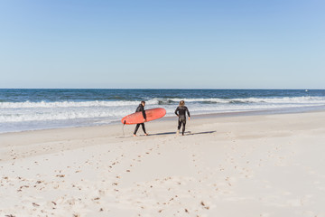 surf instructor with a student on the ocean. Surfer in a wet suit with a training board. Nazare, Portugal.