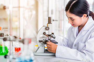 Canvas Print - Scientist sing microscope in laboratory with lab glassware containing chemical liquid, science or medical research and development concept 