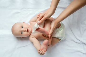 newborn baby getting a diaper change: mom wiping baby's bottom with baby wipe. emotions of newborn b